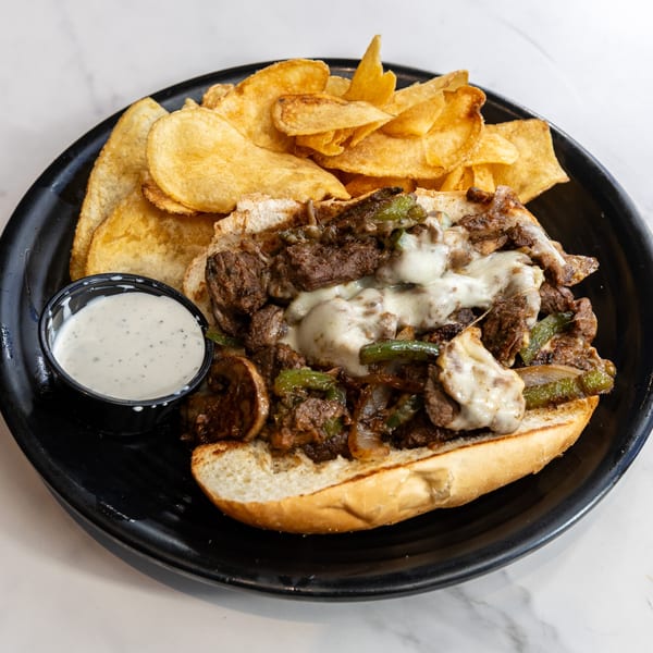 Dilworth Neighborhood Grille's cheesesteak with melted cheese, peppers, onions, and mushrooms, served with chips and ranch.